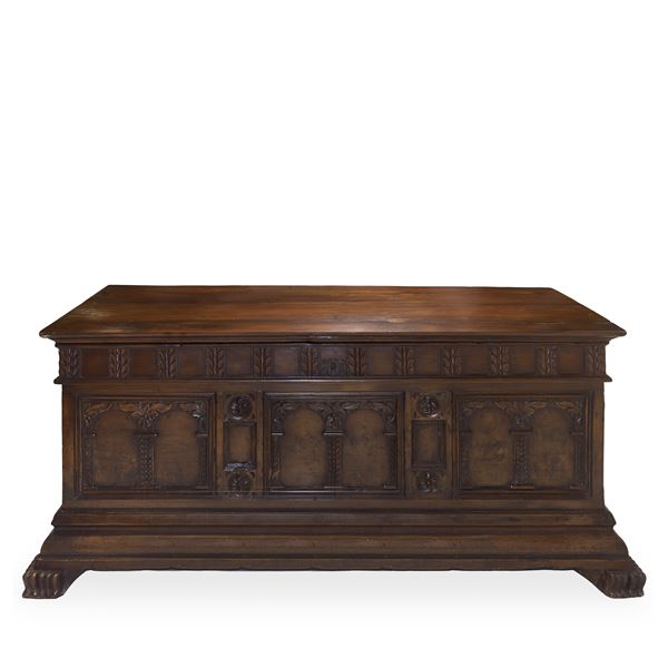 Cassapanca in noce scolpita e intagliata sul fronte con colonne ed archi, piedi felini e cornice bassa aggettante