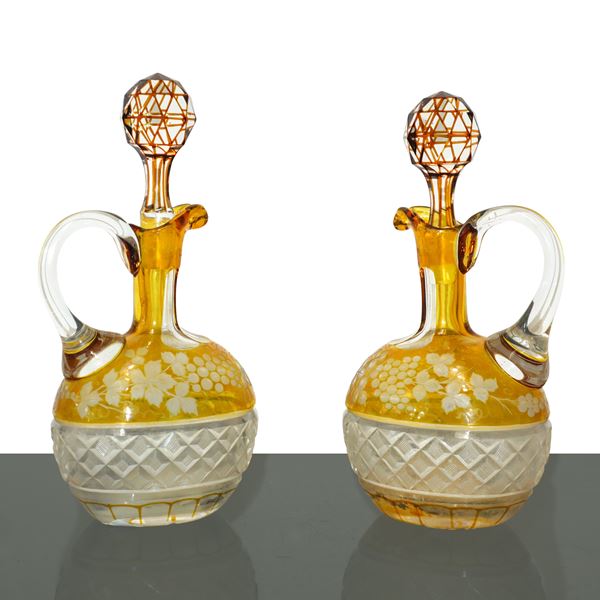 Coppia di bottiglie in cristallo di Boemia colorato nei toni del giallo bulinato a tralci d'uva e smerigliato alla base