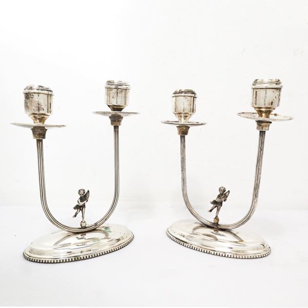 Coppia di candelabri a due fiamme in argento 800 con puttino sulla base