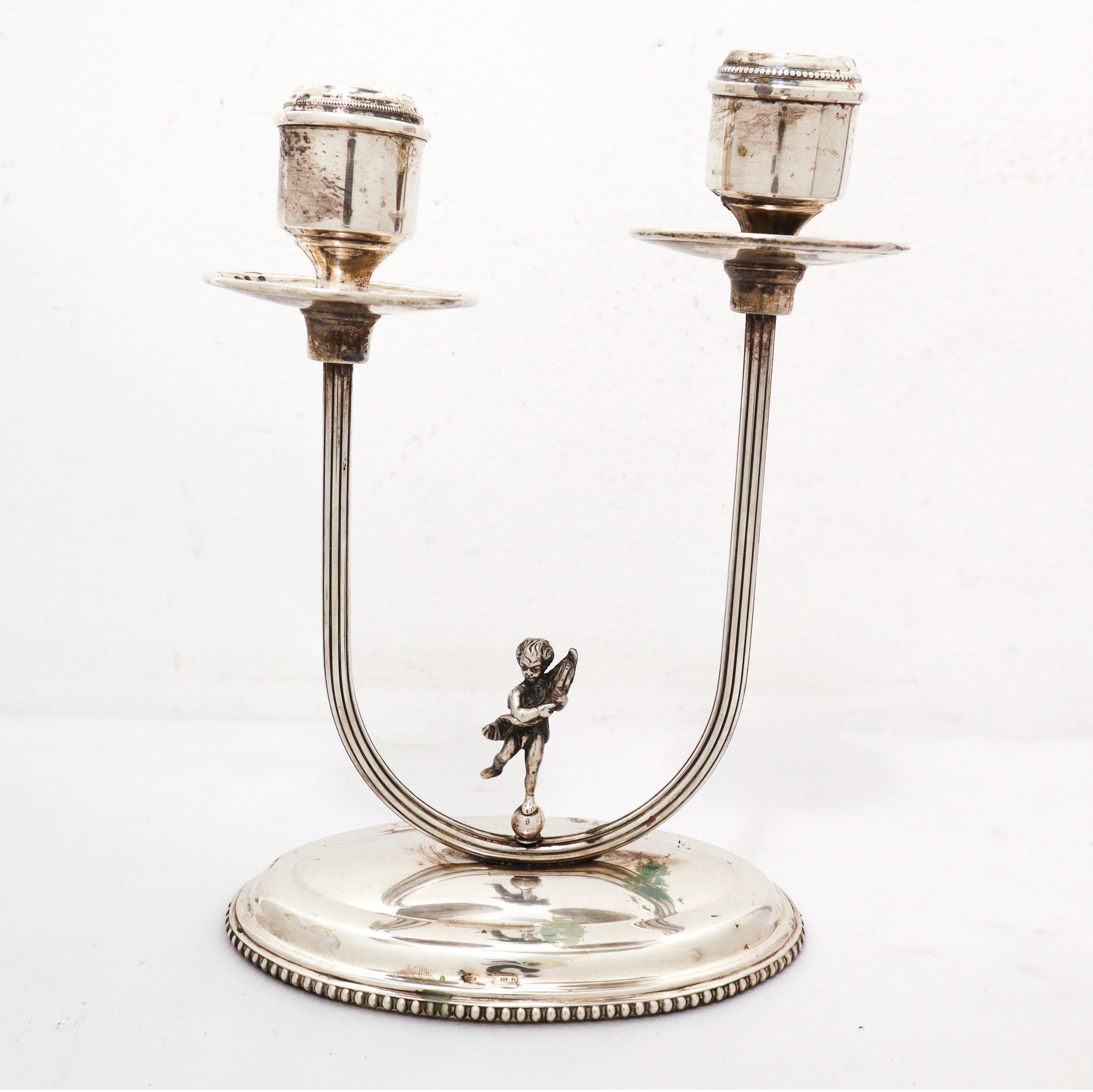 Coppia di candelabri a due fiamme in argento 800 con puttino sulla base