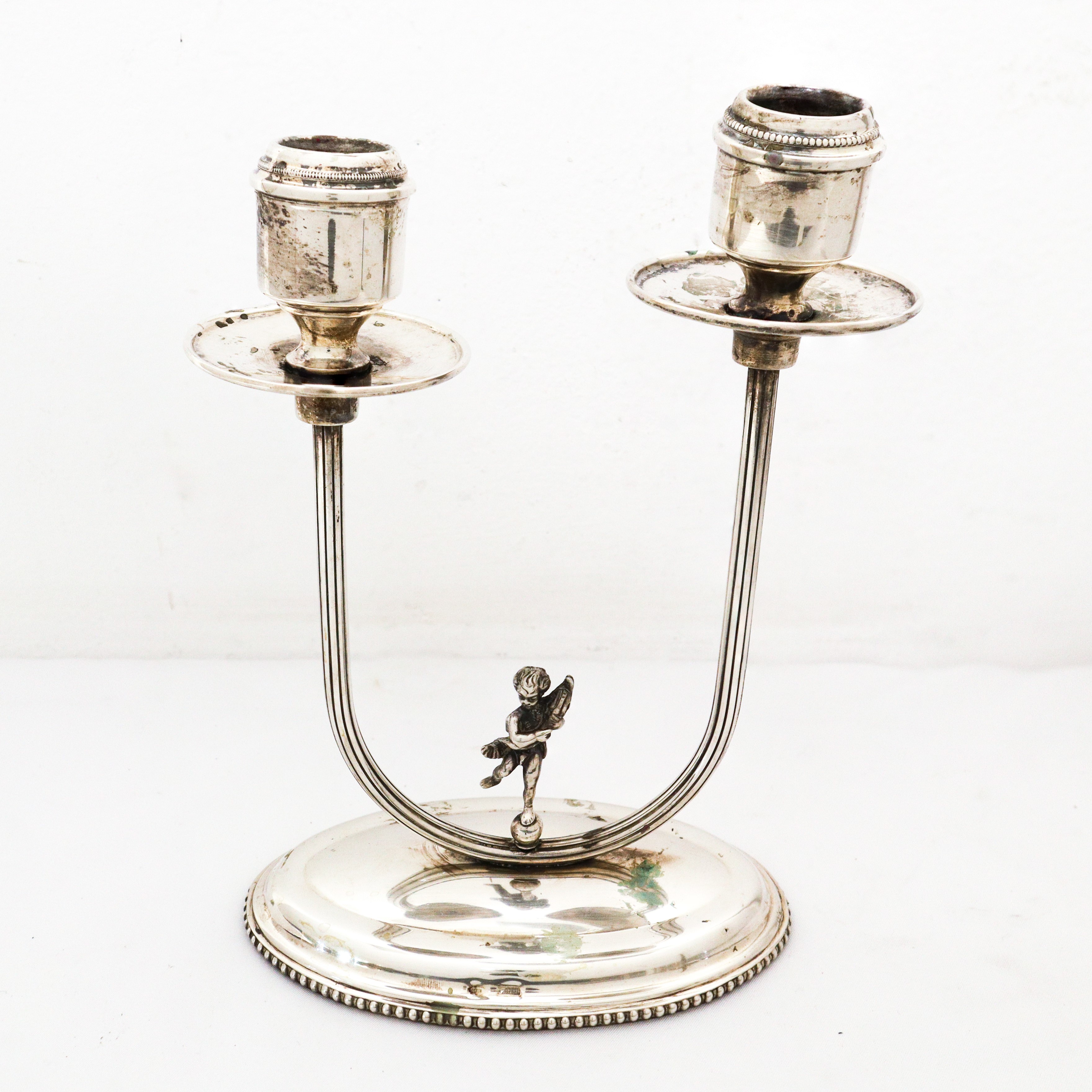 Coppia di candelabri a due fiamme in argento 800 con puttino sulla base