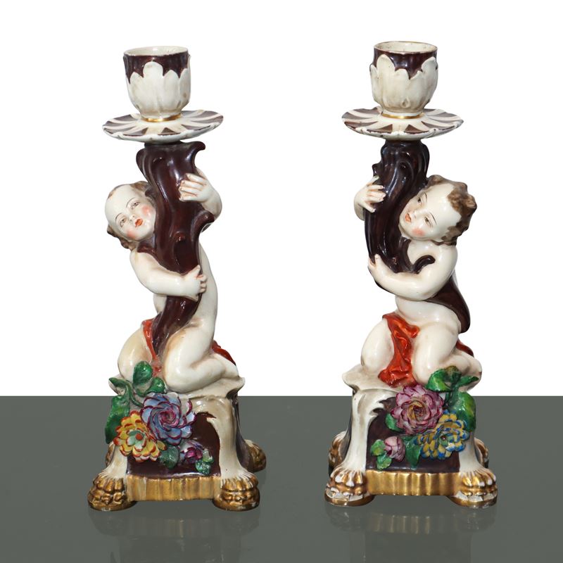 Coppia di candelieri monoforo in porcellana con putti