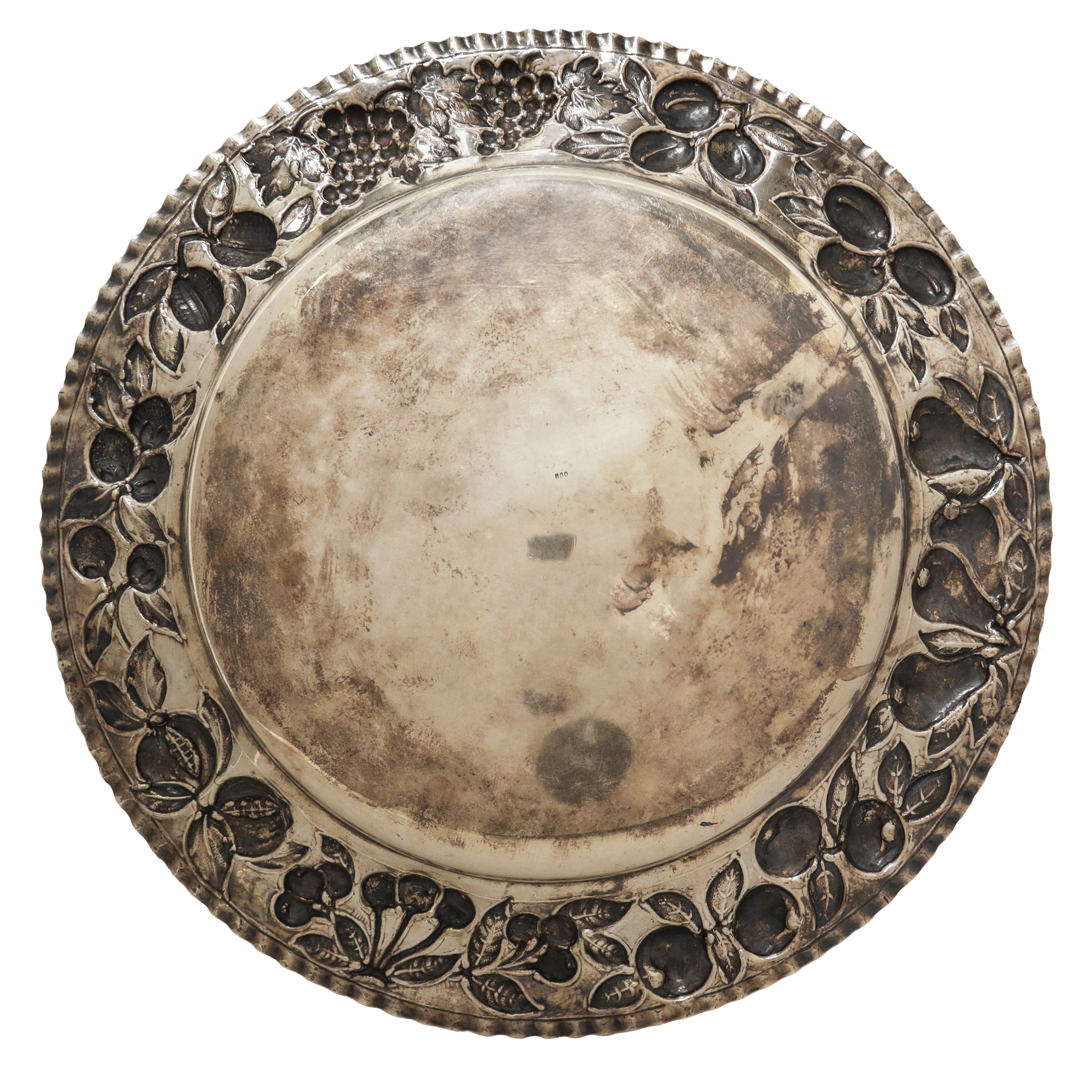 Piatto centrotavola in argento 800 con decorazioni a sbalzo di melagrane lungo il bordo lungo il ...