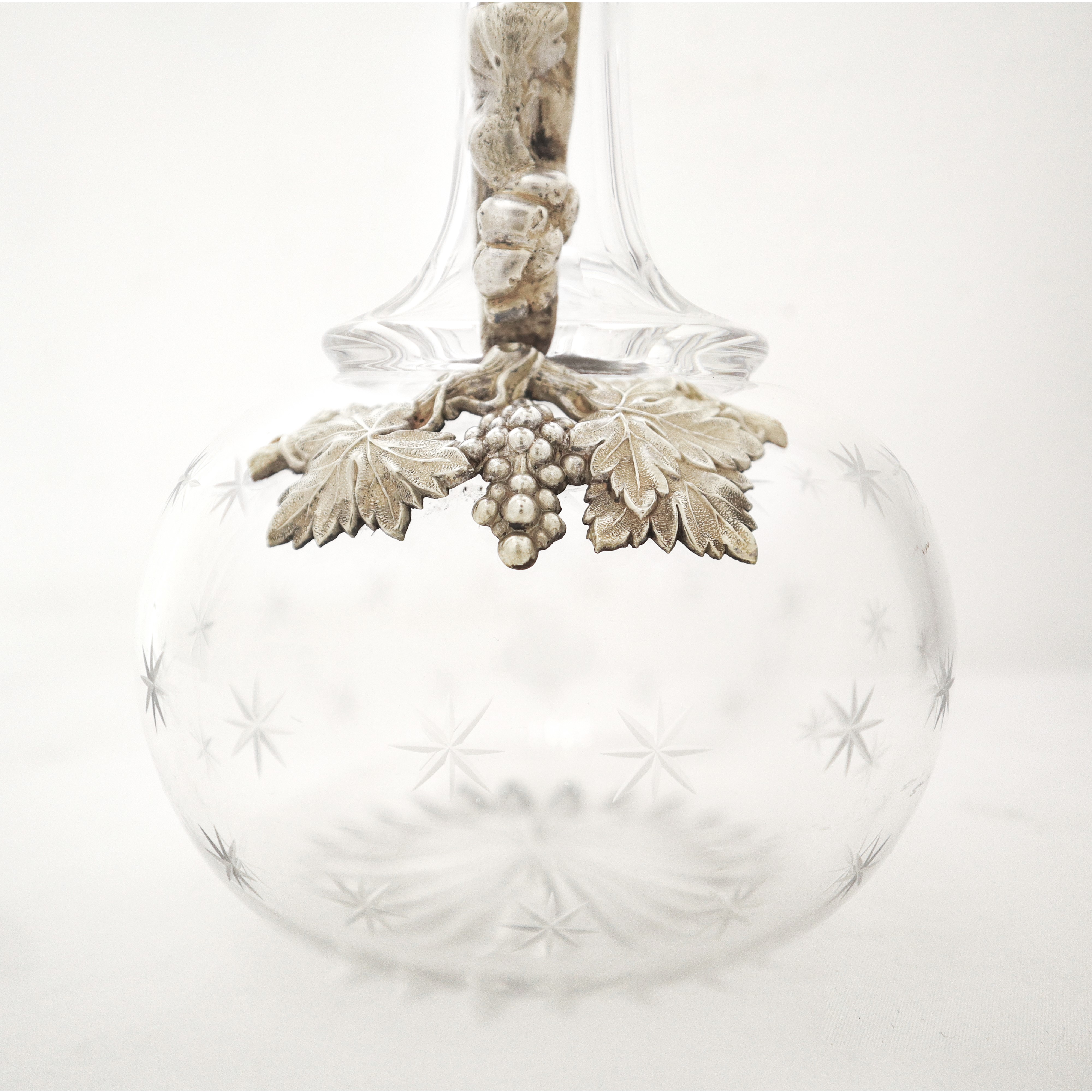 Caraffa in vetro molato con manico in metallo decorato con tralci d'uva