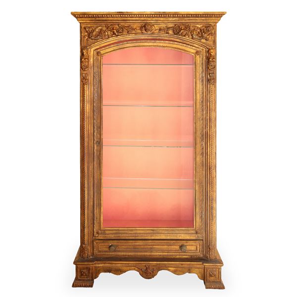 Gilded wooden display cabinet with one glass door featuring neoclassical figures, festoons and grotesques in relief. 