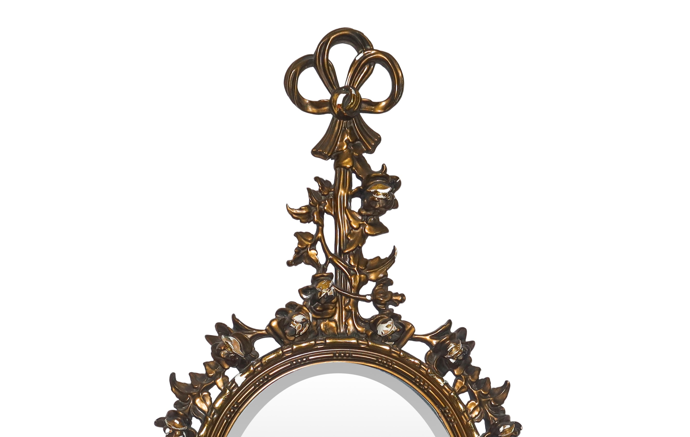 Specchiera ovale entro cornice dorata con decori floreali e fiocchi pendenti alla sommità e alla ...