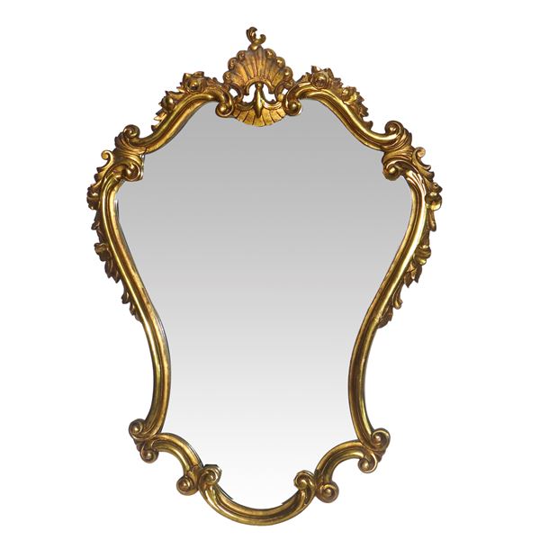 Specchiera sagomata in stile Rococò entro cornice dorata con decori e motivo a conchiglia sulla sommità