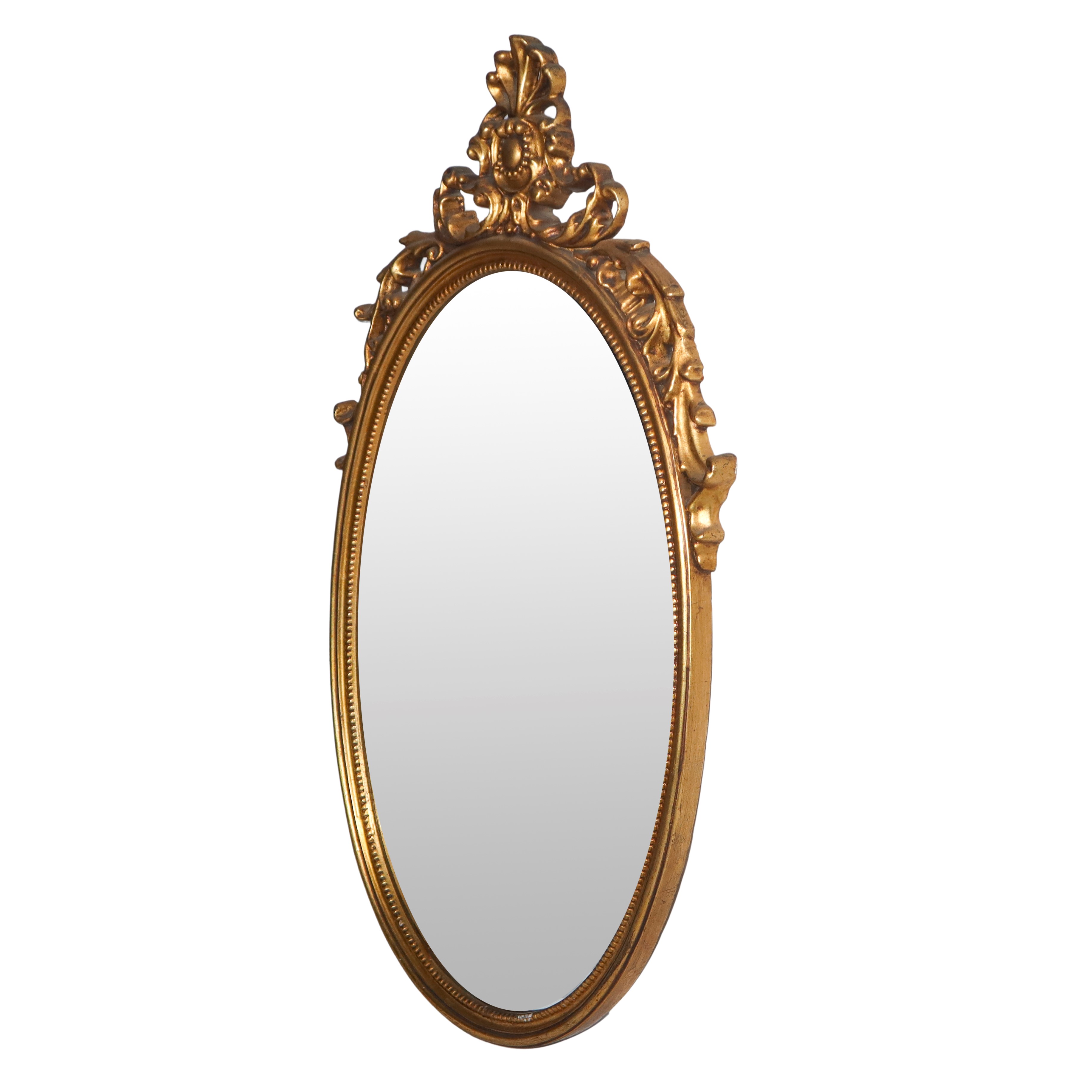 Specchiera ovale entro cornice dorata con decoro traforato sulla sommità