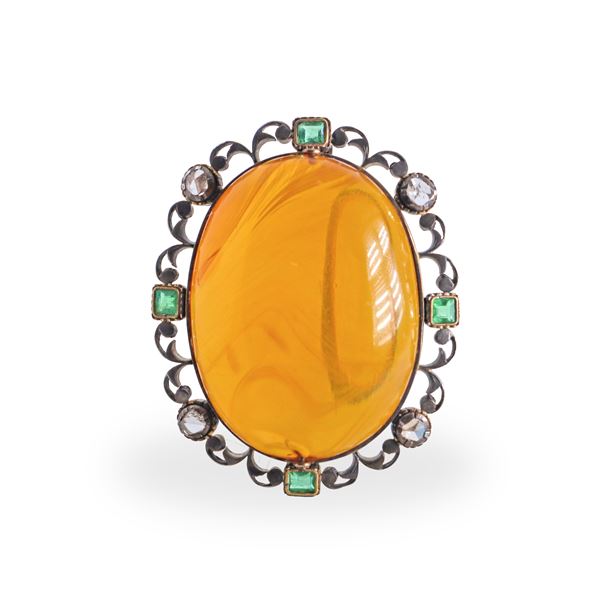 Spilla ovale in oro 750 e argento con ambra centrale e lungo il margine brillanti taglio antico e smeraldi quadrati 