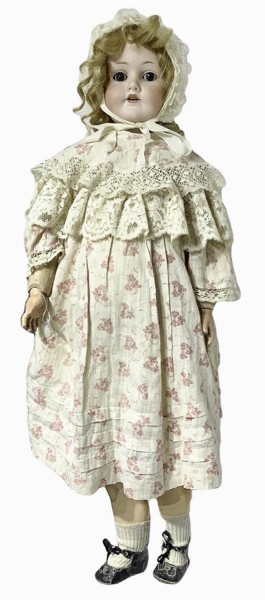 Doll in biscuit porcelain and body in composite material, white dress with floral motifs rosella, real blond hair, eyes, n. 4 teeth, movable limbs, C.M. Bergmann Waltershausen, 1900 about, origin Germany, loose elastic, black shoes with wear and tear, h 75.5 cm