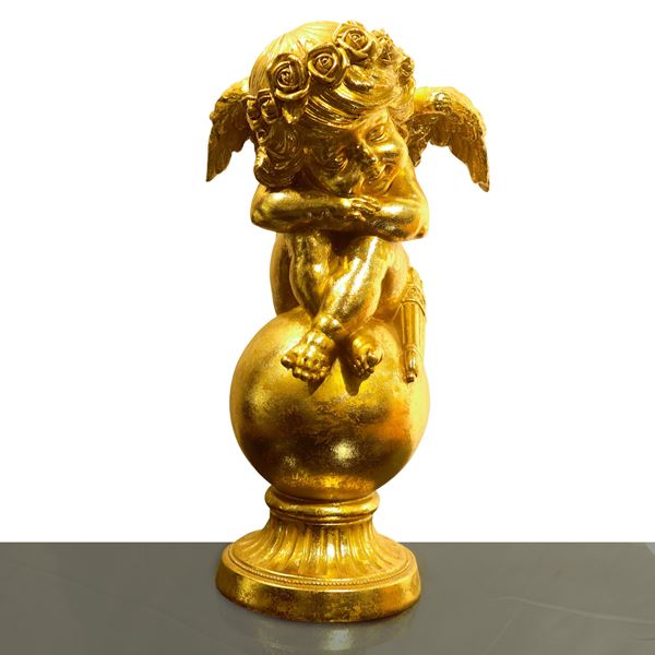 Putto dormiente dorato accovacciato su un globo