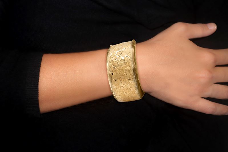 Bracciale rigido in oro giallo con decoro di trifogli satinati lungo tutto il corpo del bracciale...