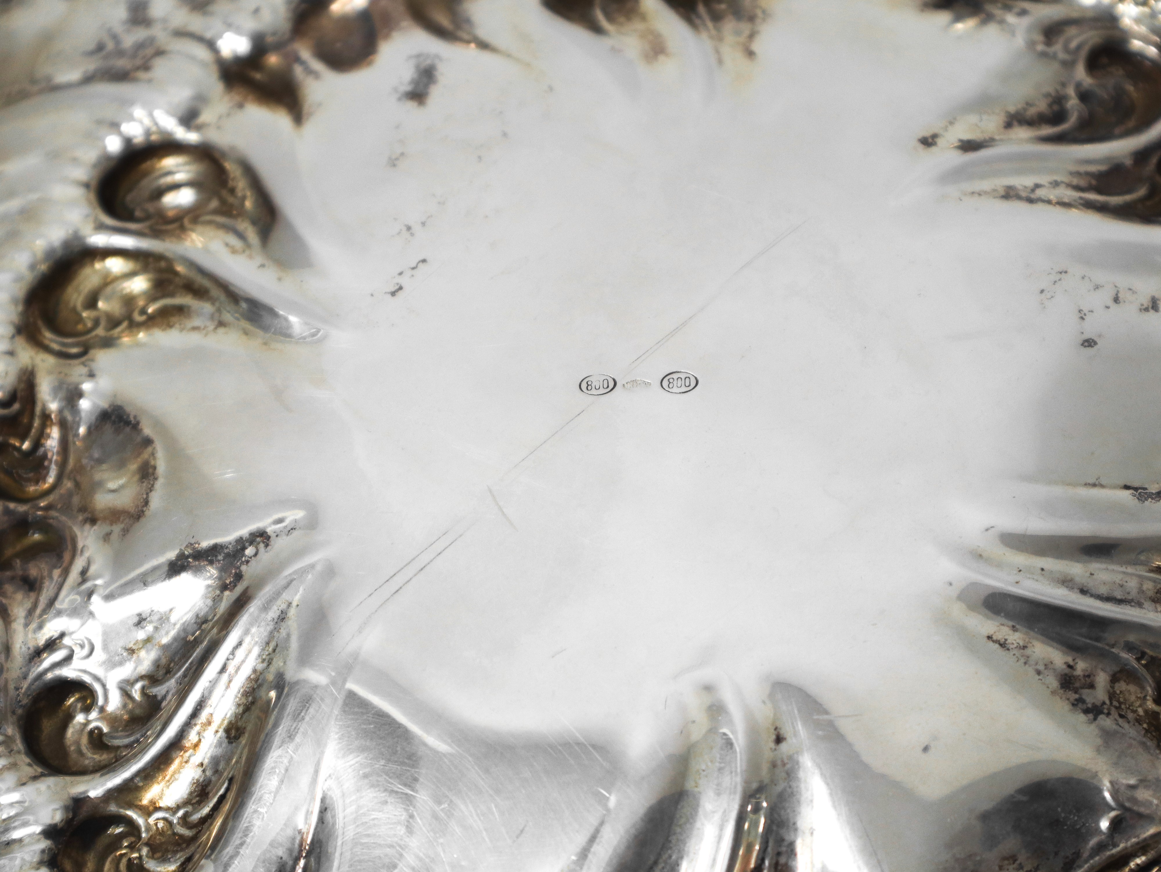Piatto centrotavola in argento 800 con decorazioni a motivi vegetali sbalzate e cesellate