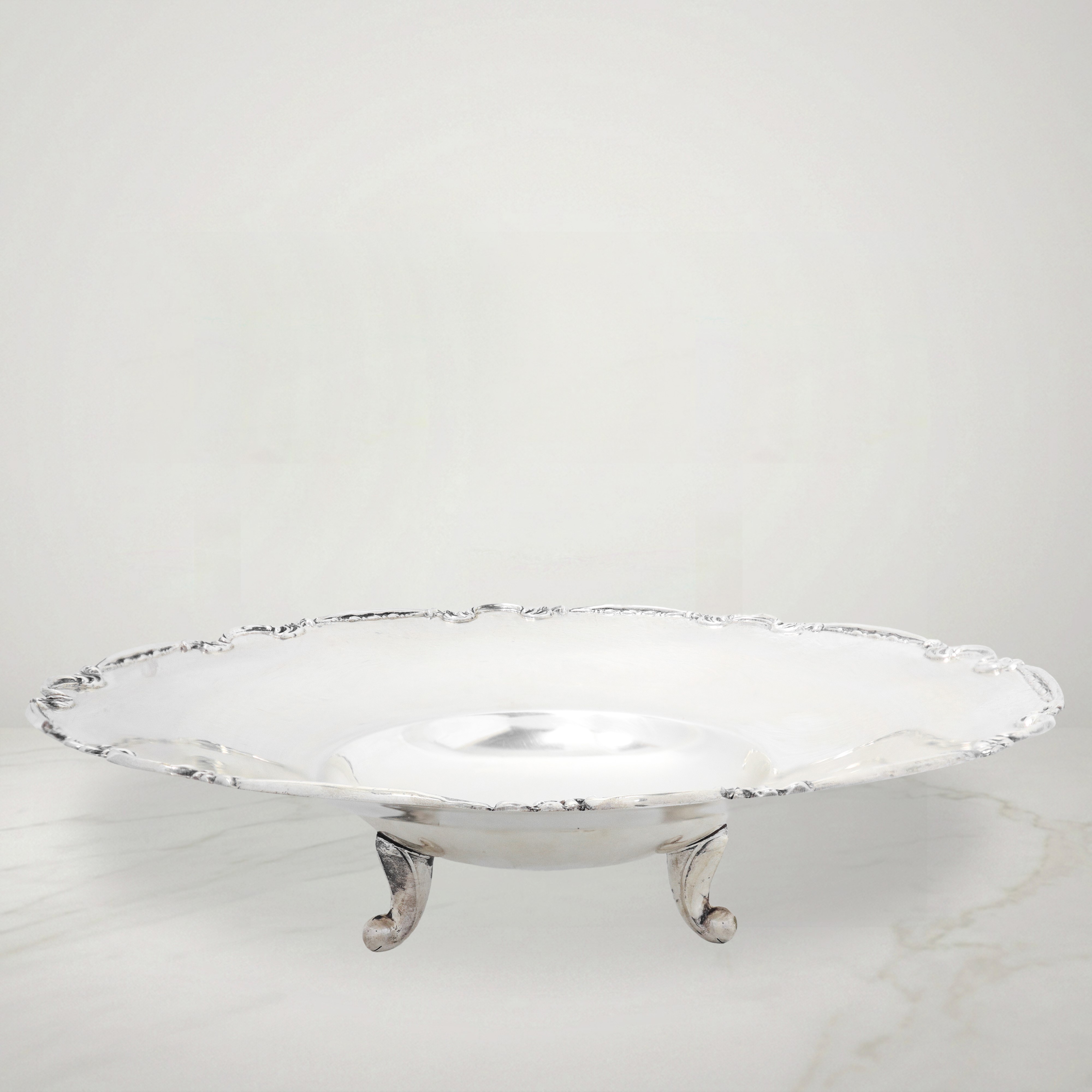 Piatto centrotavola in argento 800 con bordo decorato a volute