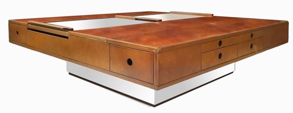 Produzione italiana attribuibile Guido Faleschini. Mobile basso in legno rivestito in radica di erica. Ante rivestite in alcantara nei toni del beige. Dettagli in alluminio lucido. Segni di uso lungo il piano e sulle ante. H cm 40 x 130 x 130. Segni d'uso