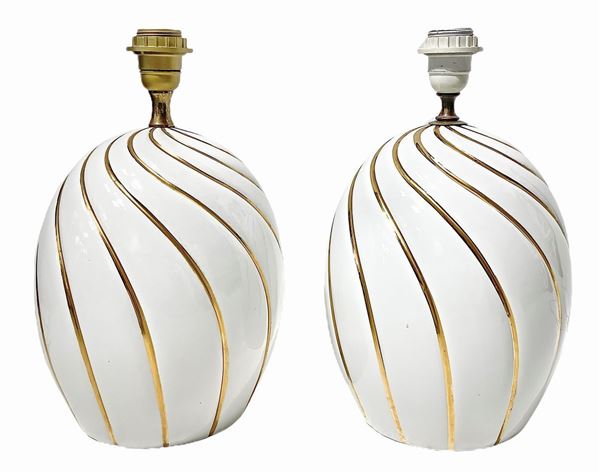 Coppia di lampade in porcellana bianca, prod italiana. Superfice riportante dettagli in oro. Anni ‘70. H cm 39. Diametro cm 22

