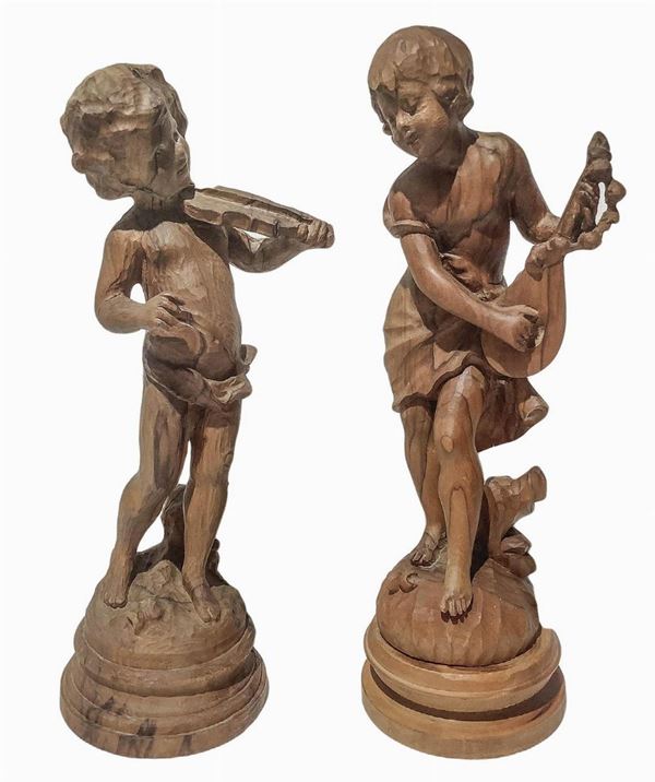 Coppia di sculture in legno raffiguranti bambini musicanti, inizi XX secolo. H cm 42