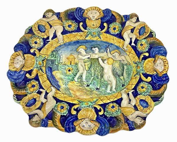 Piatto in maiolica con puttini, Centro Italia, XIX secolo. Cm 25x29,5.