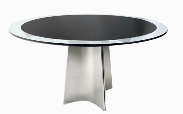 Prod. Arrmet, dis. Saccardo Luigi, mod. Ufo. Tavolo con struttura in acciaio spazzolato e dettagli in metallo laccato nero, piano in vetro con inserto adesivo in nero. Inserto adesivo con minimi difetti sulla circonferenza. Anni ‘70. Diametro cm 130, h 72 cm.