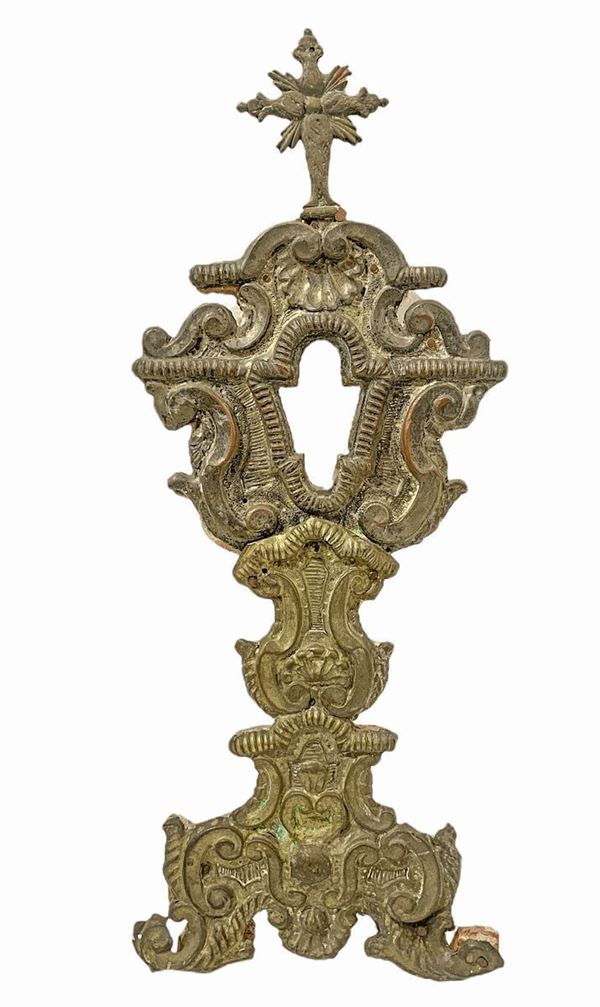 Monstrance in wood, covered with embossed brass relief, nineteenth century. H 44 cm.