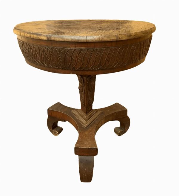 Piccolo tavolo impero, base a tre razze, piano circolare con balza intagliata, stelo con intagli di visi di donna. Inizi XIX secolo. H cm 60