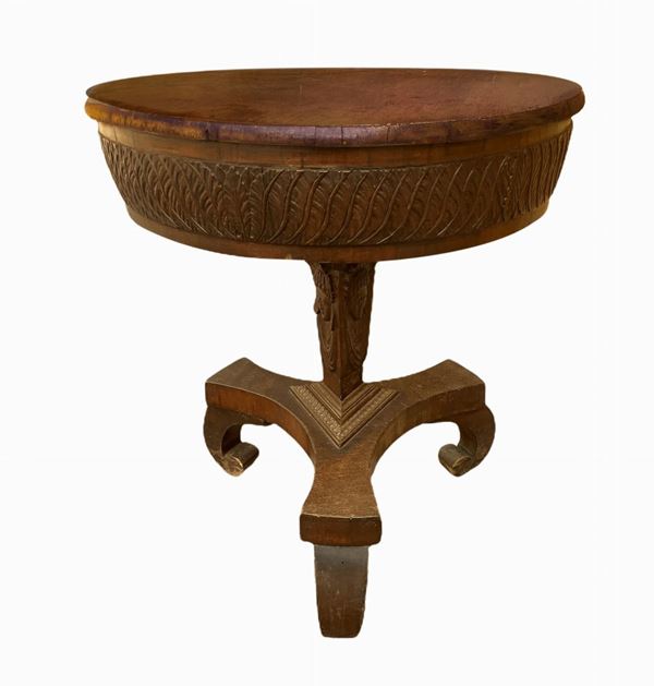Piccolo tavolo impero, base a tre razze, piano circolare con balza intagliata, stelo con intagli di visi di donna. Inizi XIX secolo. H cm 60