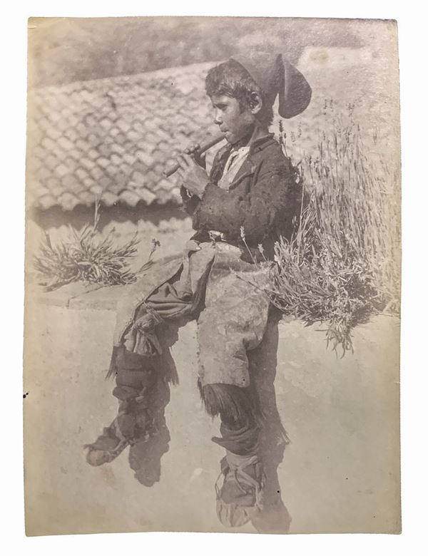 Wilhelm von Gloeden (1856-1931), foto all'albumina raffigurante giovane ragazzo siciliano che suona il flauto. Numerata a matita sul retro 434B e timbrata. Cm 12x16

"Wilhelm Von Gloeden fu un fotografo di origine tedesca che passò parte della sua vita in Sicilia, nello specifico a Taormina, città che scelse come seconda casa. Furono i problemi di salute giovanili a portarlo nella penisola. Nello specifico la scelta di Taormina è legata all'ideale onirico della Sicilia che il fotografo sprigio