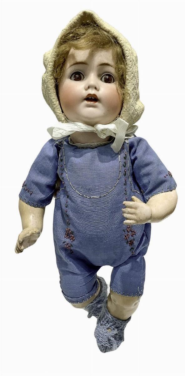 Bambola in biscuit e corpo in materiale composito, tutina azzurra con scarpette a maglia, capelli mohair, occhi mobili, n. 2 dentini, arti curvi, firma J. D. K. 257, 1912 ca., provenienza Germania, h. cm 34