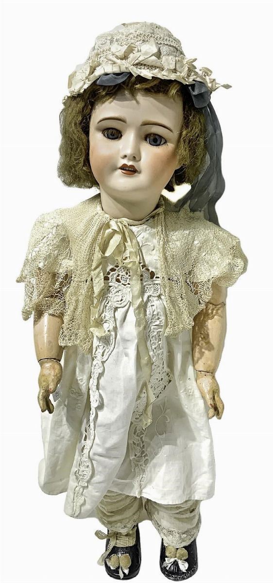Bambola in biscuit e corpo in materiale composito, abito bianco, scarpette nere, cuffietta in testa, capelli veri, occhi mobili, n. 6 dentini, arti mobili, firma Unis Francia 301, 1899 ca, provenienza Parigi, h cm 74