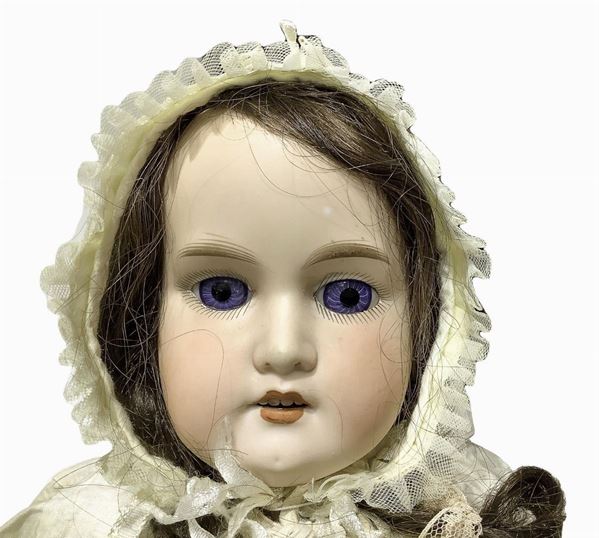 Bambola in biscuit e pelle di capretto, abito panna ricamato con cuffietta, capelli veri, occhi fissi, n. 4 dentini, arti in biscuit e pelle di capretto, firma 370 A7 M., 1900 ca., provenienza Germania, h cm 58, si segnala la scrostatura delle dita della mano destra