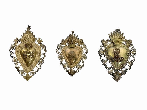 N 3 Ex silver vermeil ex-voto in a heart shape with cupids and zephyrs. 1) H 21 cm 2) H 22 cm 3) H 23 cm