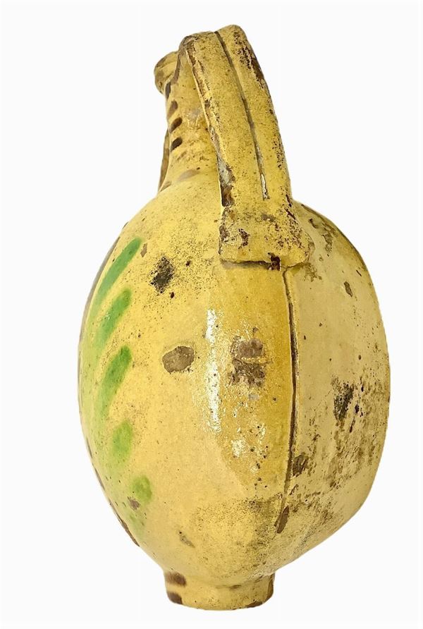 Fiaschetta biansata in terracotta maiolicata di Caltagirone, Sicilia,  fine sexolo XIX . Nei toni del giallo, verde e bruno. Al centro fiore stilizzato. H cm 23x17