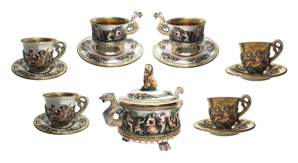 Servizio da tè e caffè in porcellana, marchio Capodimonte 2226. Composto da zuccheriera (H cm14x15), 2 tazze da tè (H cm 7, diam. cm 8), 2 tazze da caffè (H cm 6, diam. cm 7), 2 tazze da caffè (H cm 6,5, diam. cm 7). Decorazione con figure in altorilievo e scene di genere.