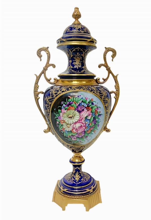 Vaso in porcellana, stile Sevres, in colore blu con manici dorati e decorazioni floreali. H cm 61. 
H cm 61