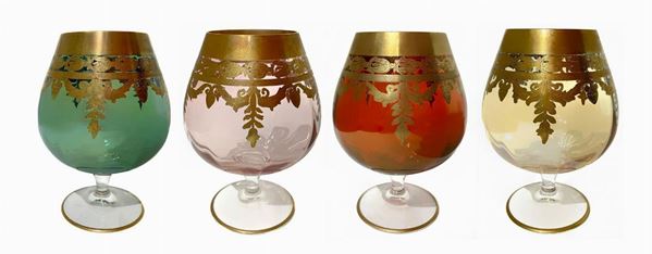 Quattro bicchieri da cognac in vetro di Murano in quattro colori con bordo e decorazioni in oro zecchino. H Cm 15.
