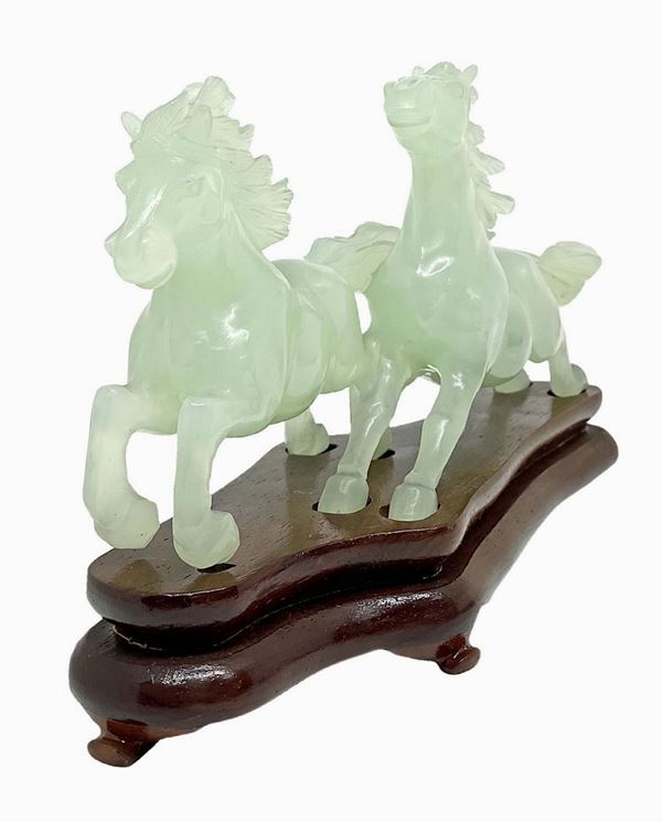 Coppia di cavalli cinesi in giada verde chiaro con base in legno.