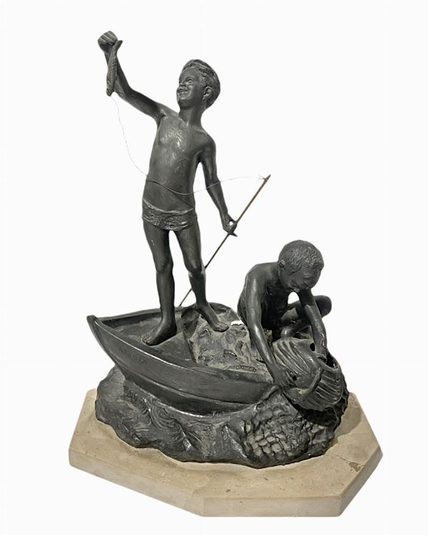 Scultura in antimonio patinato bronzo raffigurante coppia di scugnizzi su barca. XX secolo. Firma sul retro P. Uccello. H cm 39
