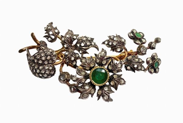 Brooch with flowers and leaves in gold and silver with 1 central root emerald and 2 on the side side, and crowns small roses and small roses of mis diamonds. 8 Cm