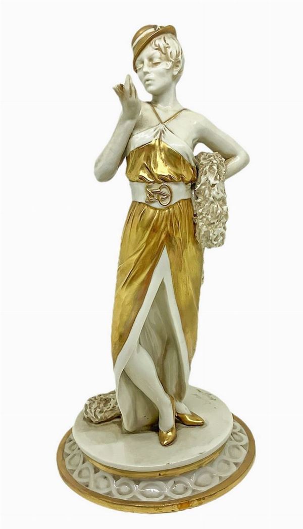 Capodimonte, statuetta in porcellana raffigurante donna con cappello e stola in pelliccia. nei colori del bianco ed oro.
H cm 23, base cm 11