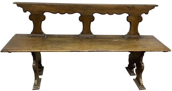 Panca in legno di noce con spalliera e seduta pieghevole, XVII secolo. Spalliera con decoro ad asso di coppe, piedi a lira. H cm 95xcm H 180x44.
