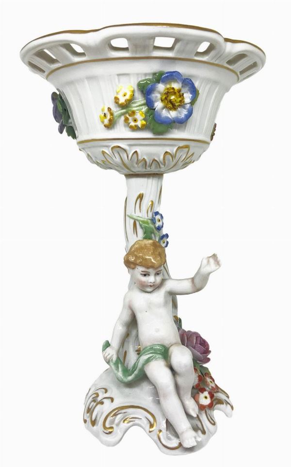 Alzata in porcellana di Capodimonte con decori floreali e piccolo amorino alla base. 
H cm 20